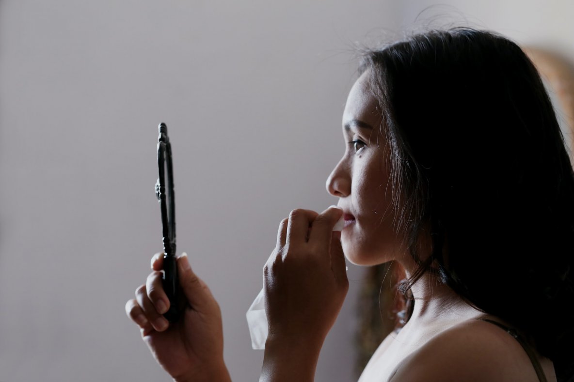 woman looking at acne in the mirror