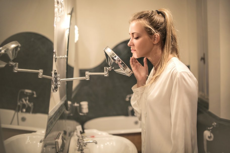 woman looking at acne scars in the mirror